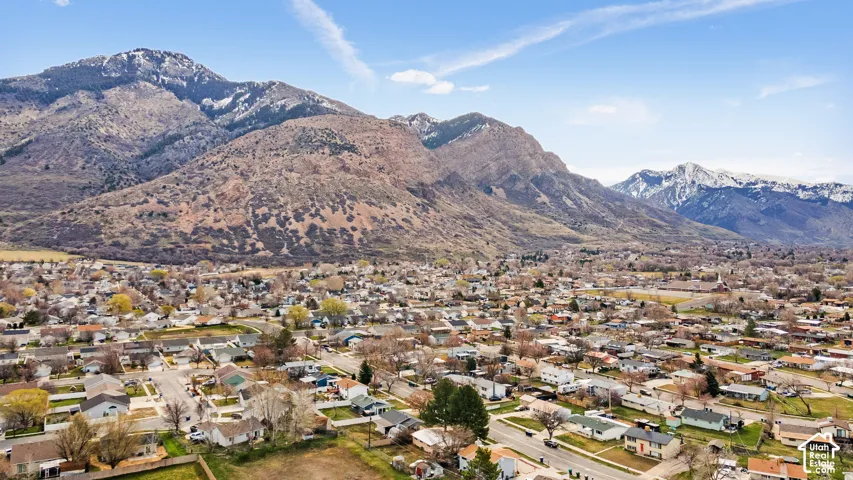 Expansive residential area with a mountain backdrop, featuring a clear sky, mature trees, and a mix of single-story and multi-story homes