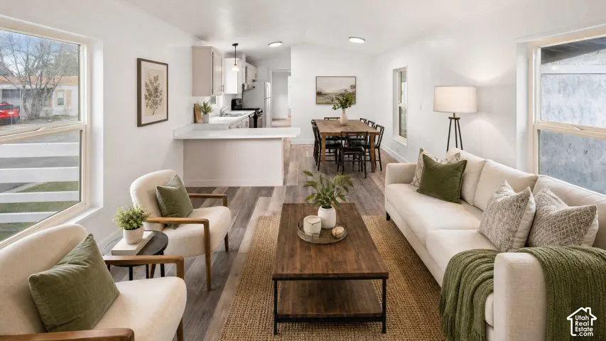 Open-concept living space featuring wood-finish flooring, recessed lighting, a breakfast bar with a light-toned countertop, and light-colored cabinetry