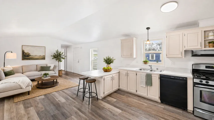 Open-concept living space featuring wood-finish flooring, white walls, and vaulted ceilings