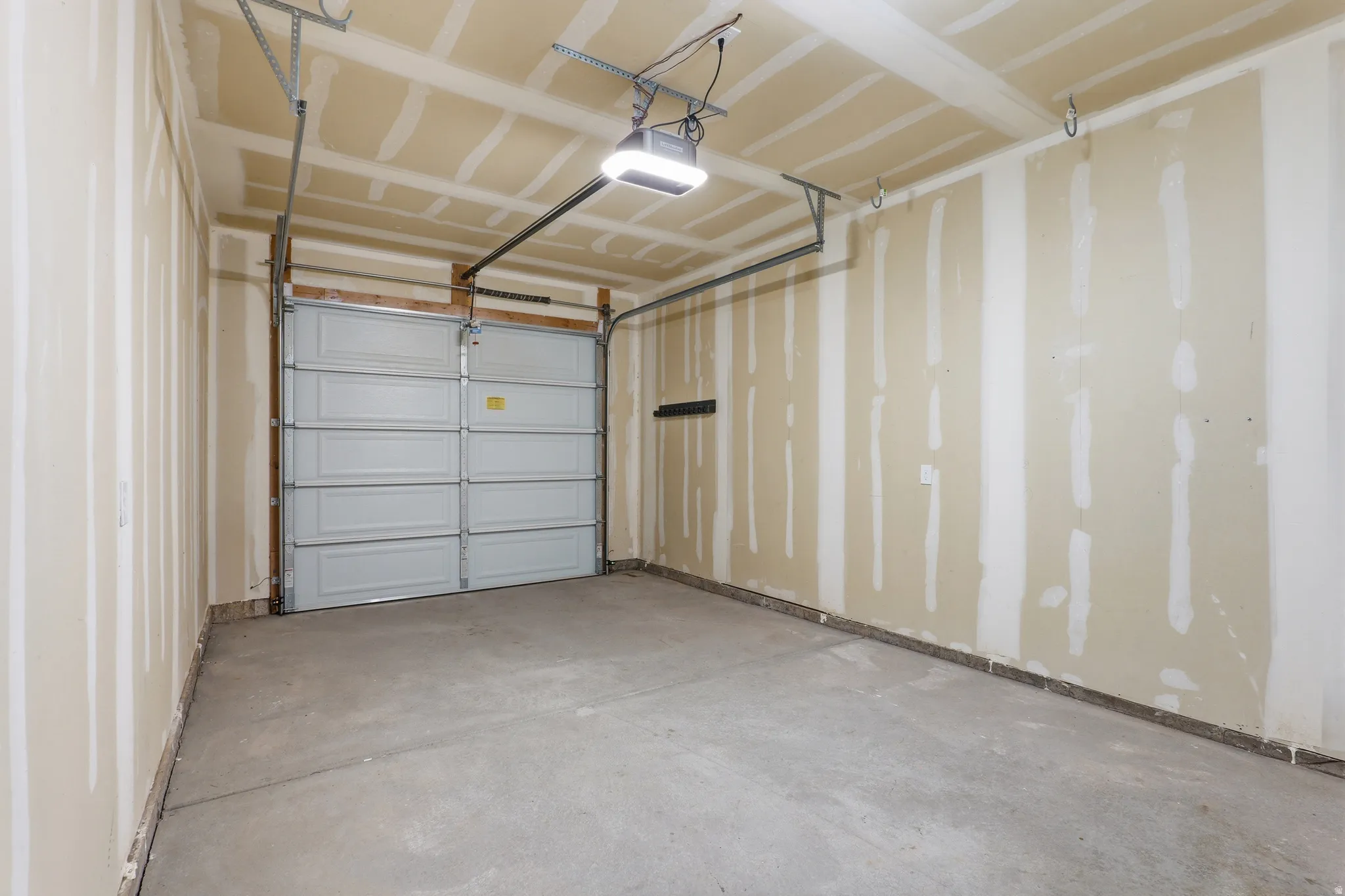 Spacious garage featuring a concrete floor, overhead lighting fixture, and a sectional garage door