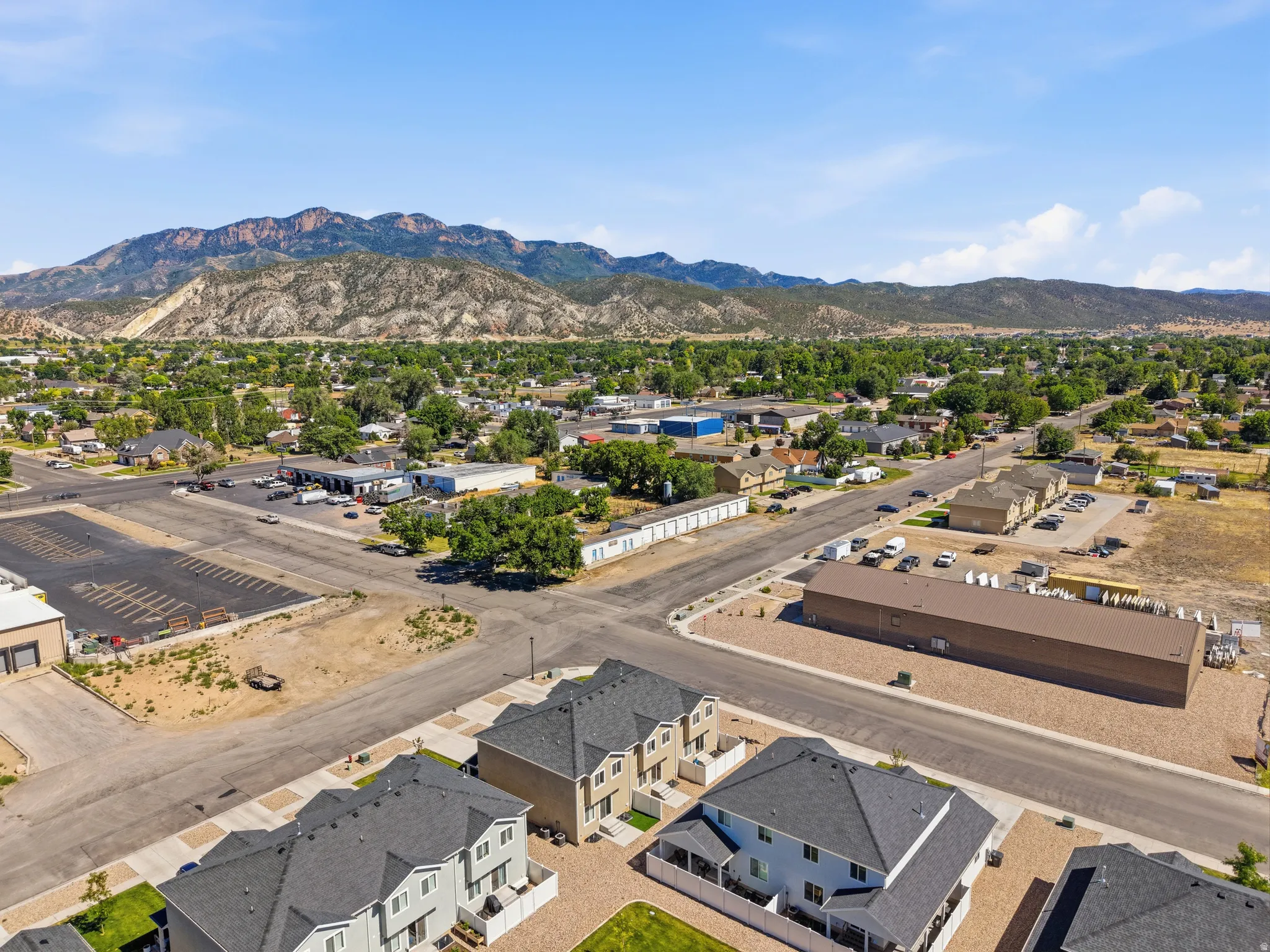 Elevated perspective showcasing a mixed-use neighborhood with residential properties, commercial structures, and undeveloped land