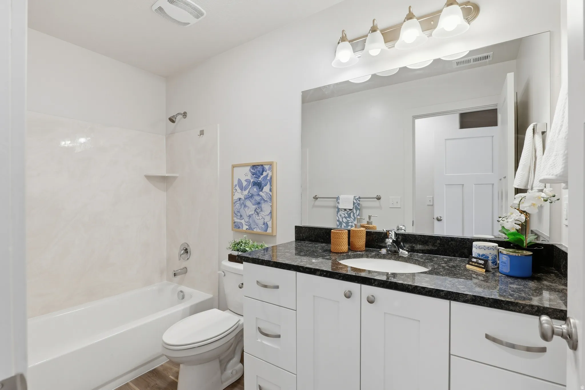 Bathroom featuring a dark granite-style countertop, undermount sink, and extensive white cabinetry