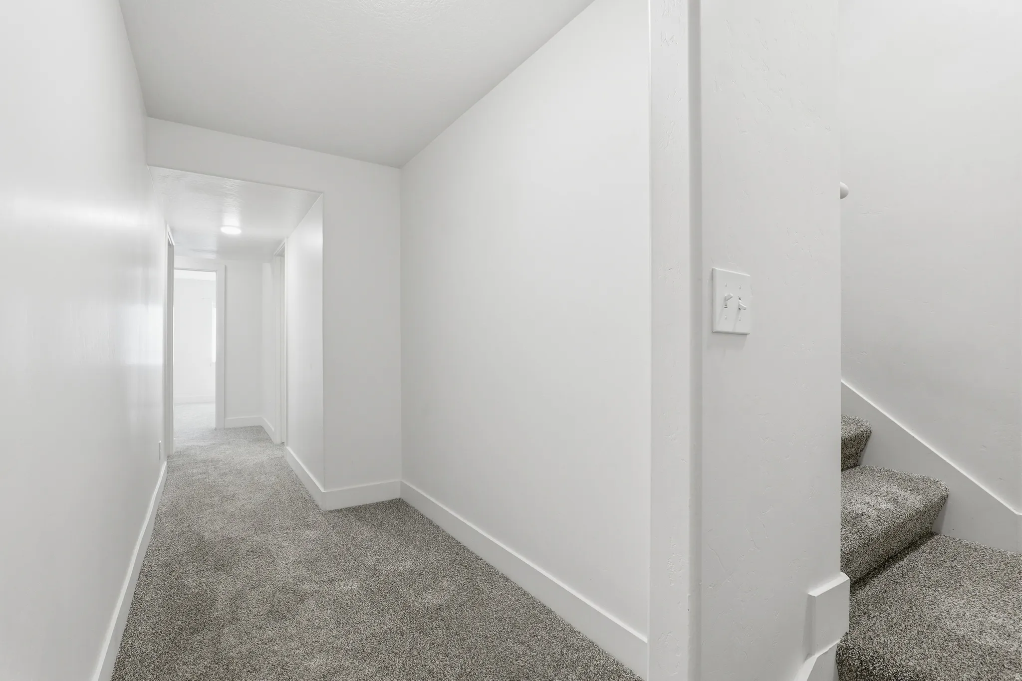 Hallway featuring grey carpeting and white baseboards