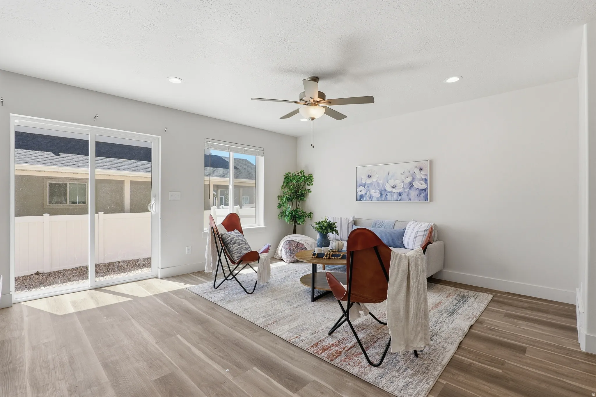 Bright living space featuring wood-finish flooring, recessed lighting, and a ceiling fan