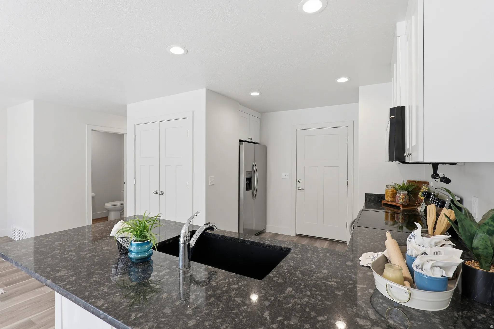 Kitchen island with dark speckled countertop, undermount sink, and gooseneck faucet