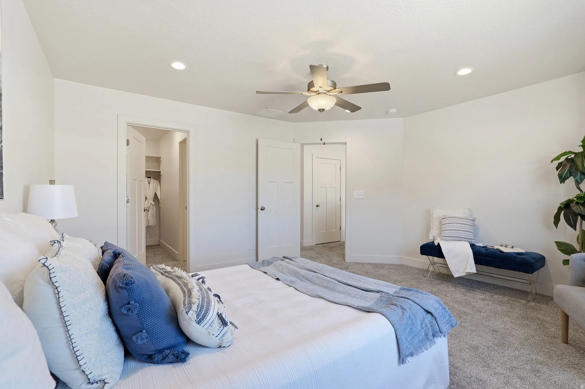 Spacious bedroom with light gray carpeting, recessed lighting, and a ceiling fan
