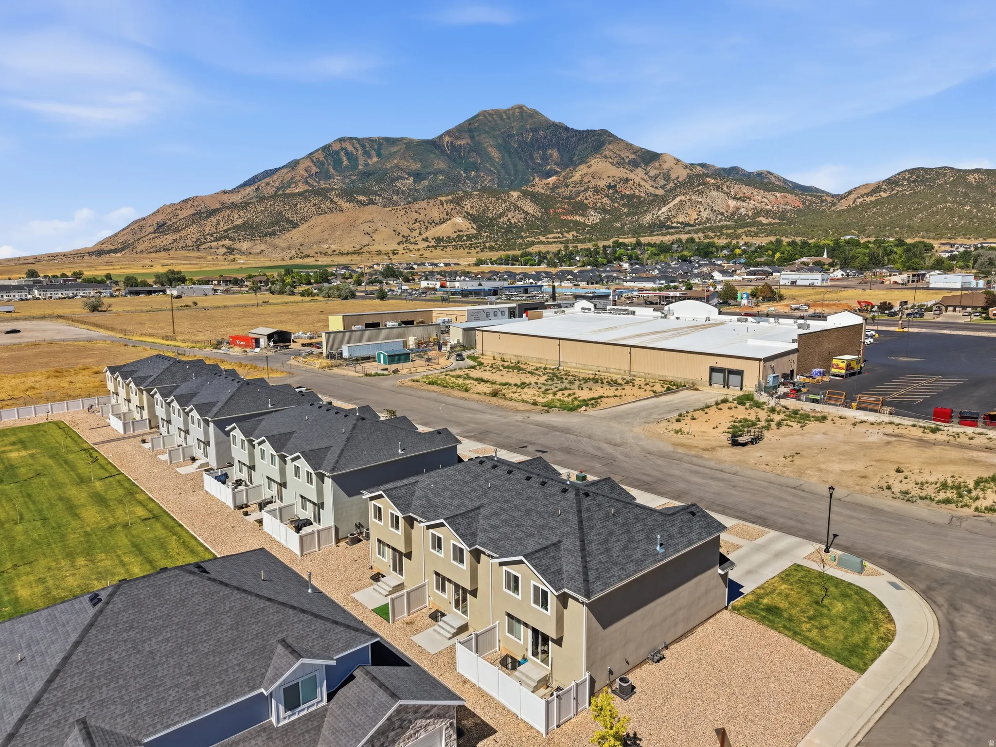 Row of townhomes featuring contrasting siding colors, dark shingle roofs, and individual fenced patios