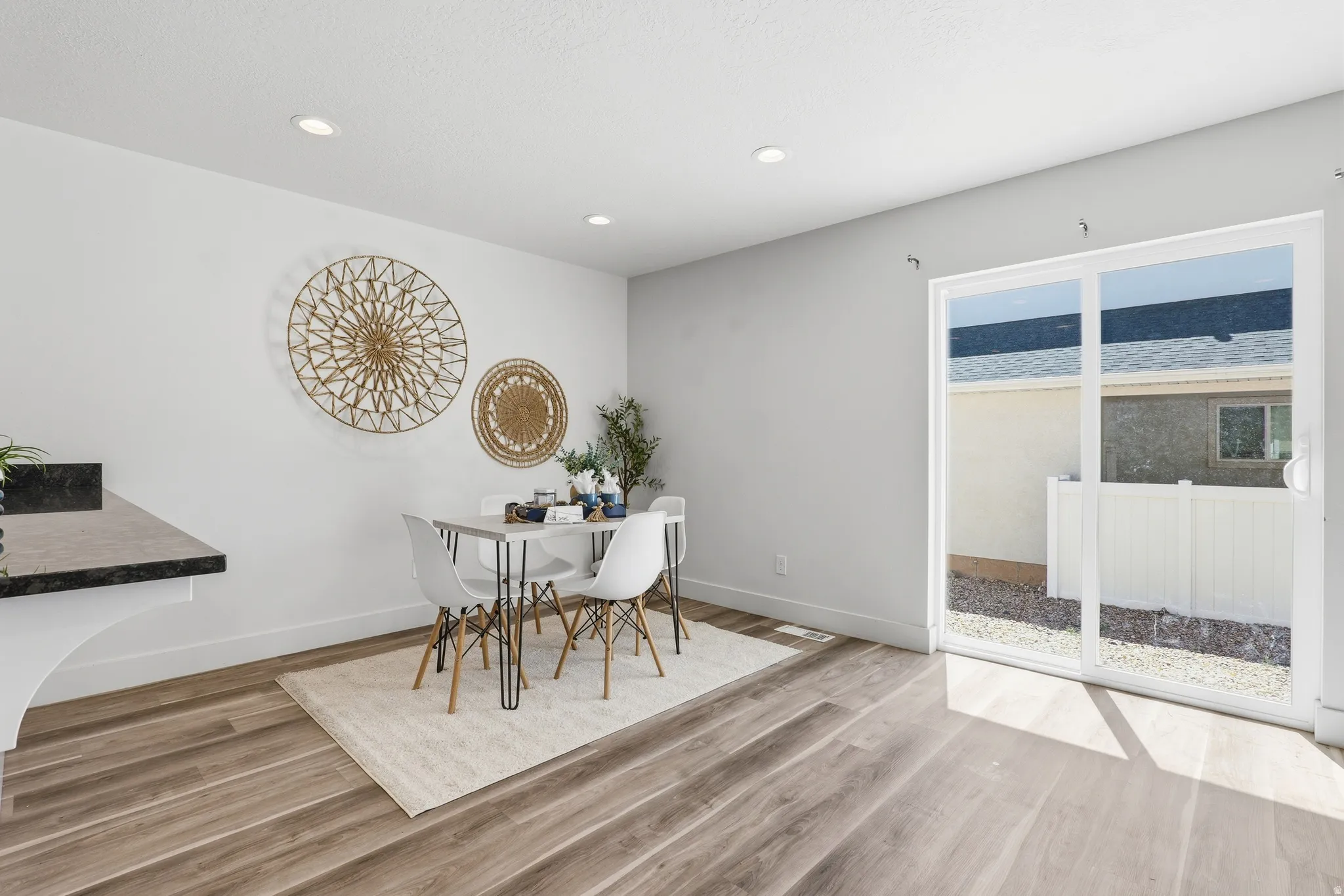 Open-concept dining area featuring wood-finish flooring, recessed lighting, and a sliding glass door providing access to the outdoor space