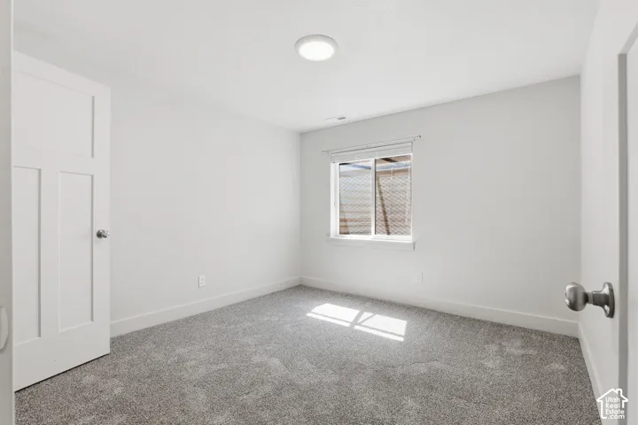 Bright room featuring neutral gray carpeting and a single window with blinds