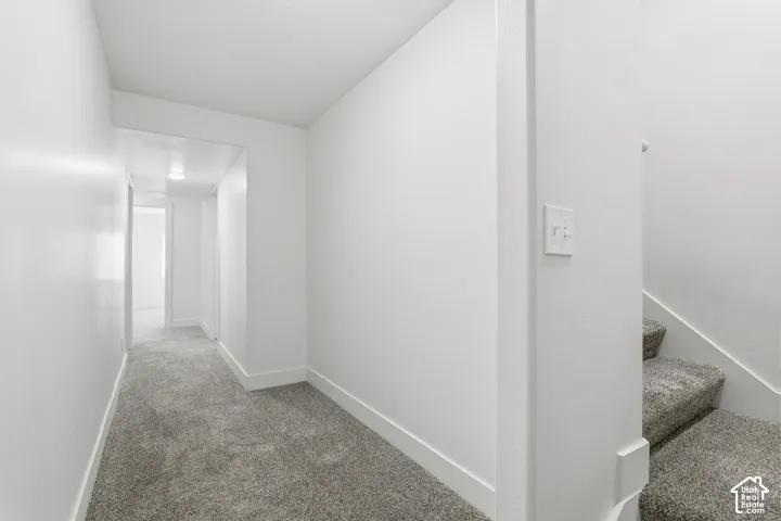 Hallway featuring grey carpeting and white baseboards