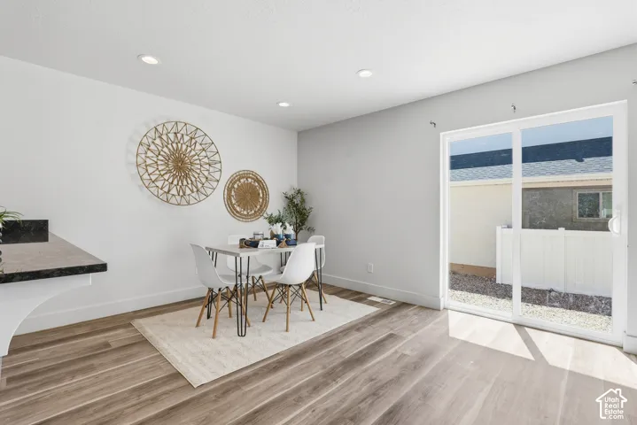 Open-concept dining area featuring wood-finish flooring, recessed lighting, and a sliding glass door providing access to the outdoor space