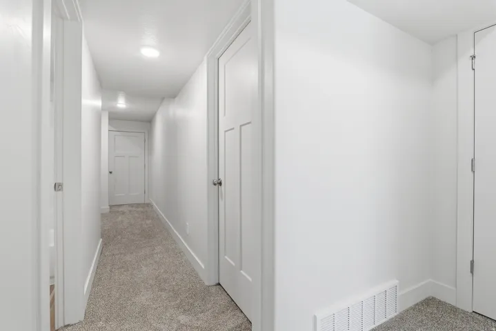 Hallway with neutral carpeting, recessed lighting, white panel doors, and crisp white trim