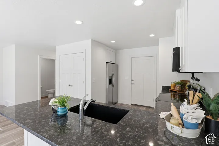 Kitchen island with dark speckled countertop, undermount sink, and gooseneck faucet