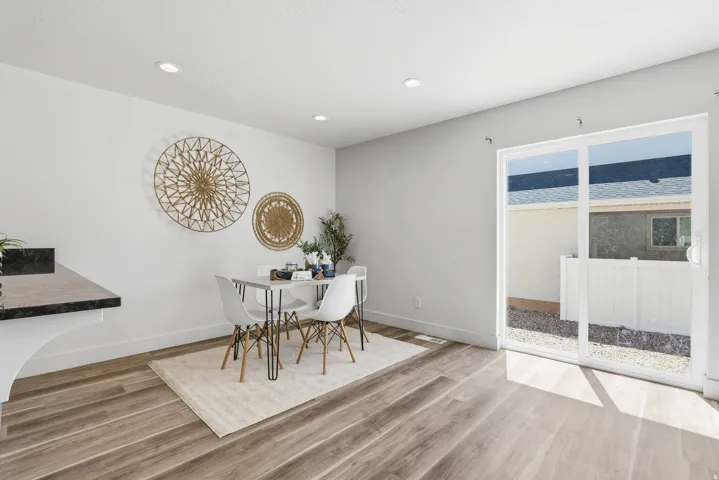 Open-concept dining area featuring wood-finish flooring, recessed lighting, and a sliding glass door providing access to the outdoor space