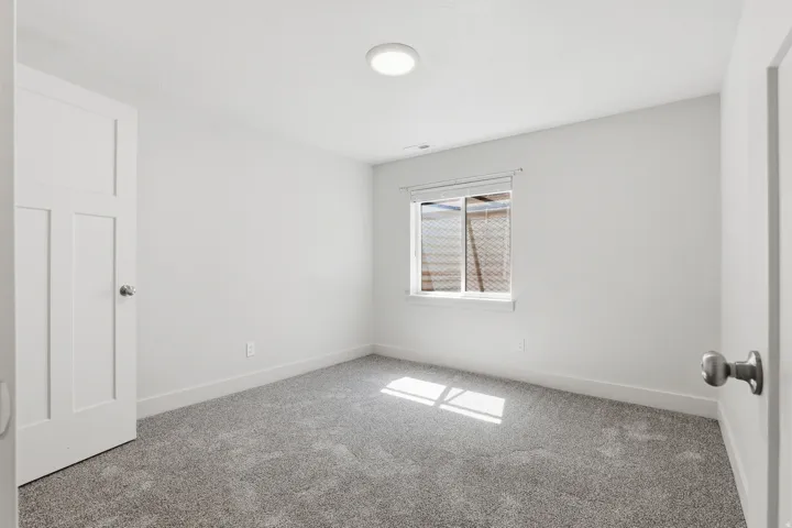 Bright room featuring neutral gray carpeting and a single window with blinds