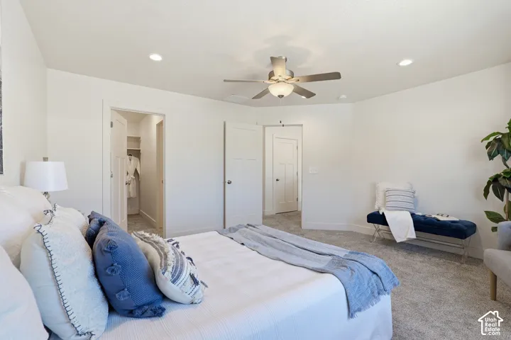 Spacious bedroom with light gray carpeting, recessed lighting, and a ceiling fan
