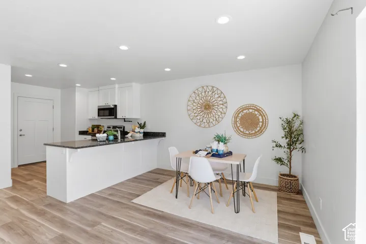 Open-concept dining area featuring wood-finish flooring, white walls, and recessed lighting