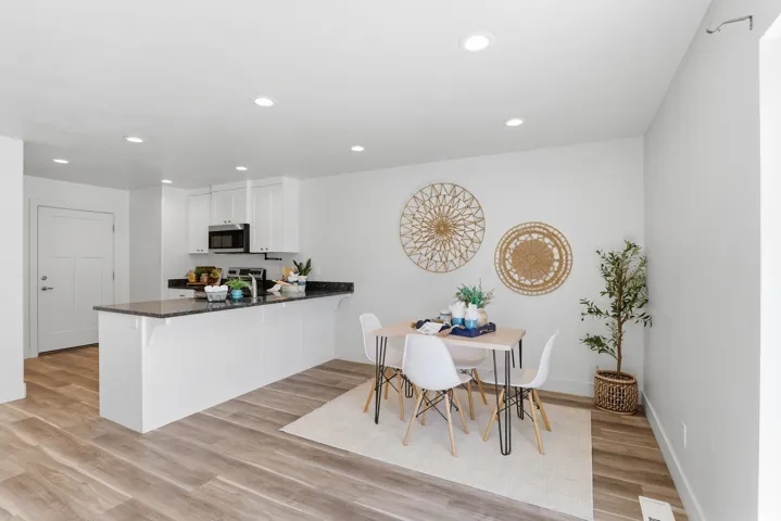 Open-concept dining area featuring wood-finish flooring, white walls, and recessed lighting