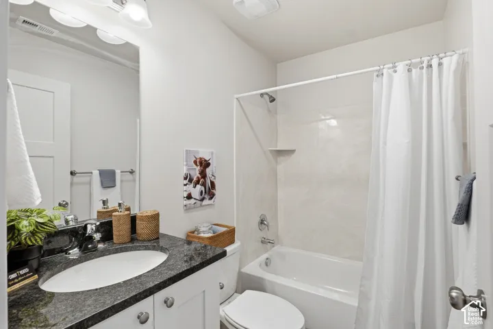 Bathroom featuring a vanity with a dark speckled countertop, an undermount sink, and white cabinetry