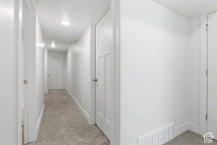 Hallway with neutral carpeting, recessed lighting, white panel doors, and crisp white trim
