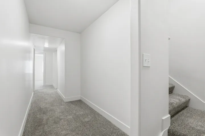 Hallway featuring grey carpeting and white baseboards