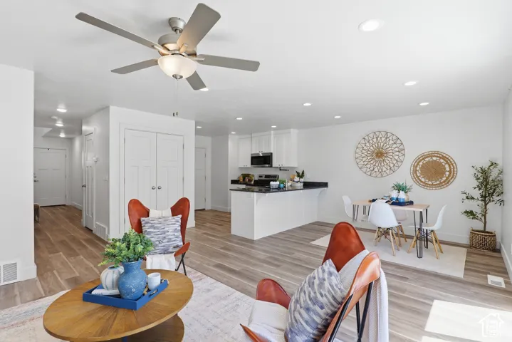 Open-concept living area with wood-finish flooring, recessed lighting, and a ceiling fan