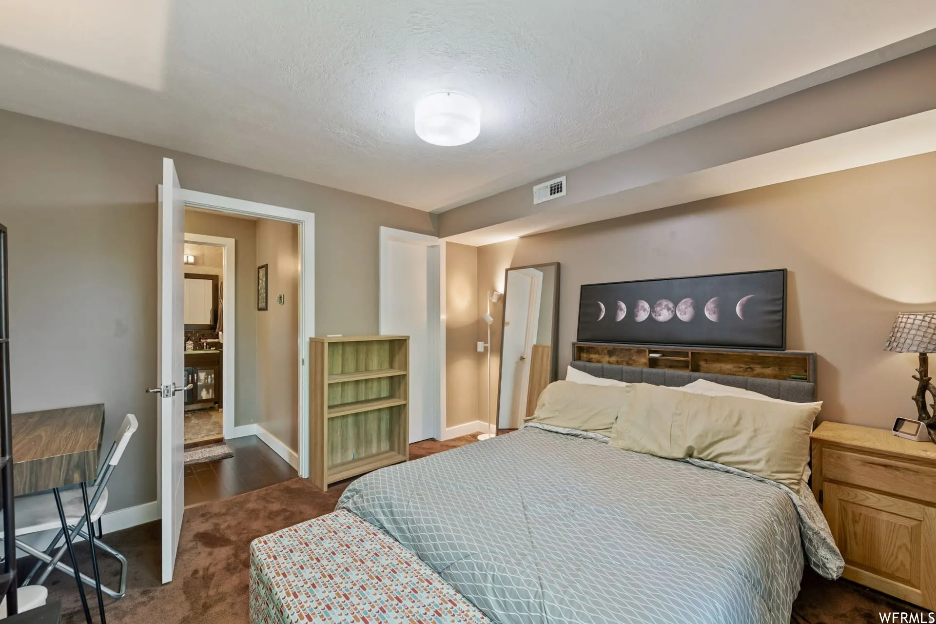 Carpeted bedroom with neutral wall tones and a ceiling-mounted light fixture