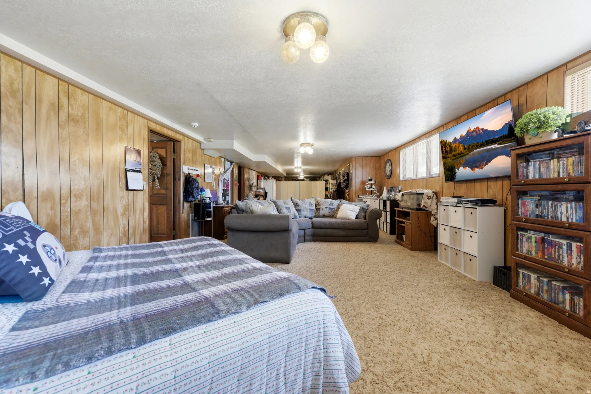 Spacious room featuring wood paneling, recessed lighting, and a neutral carpeted floor