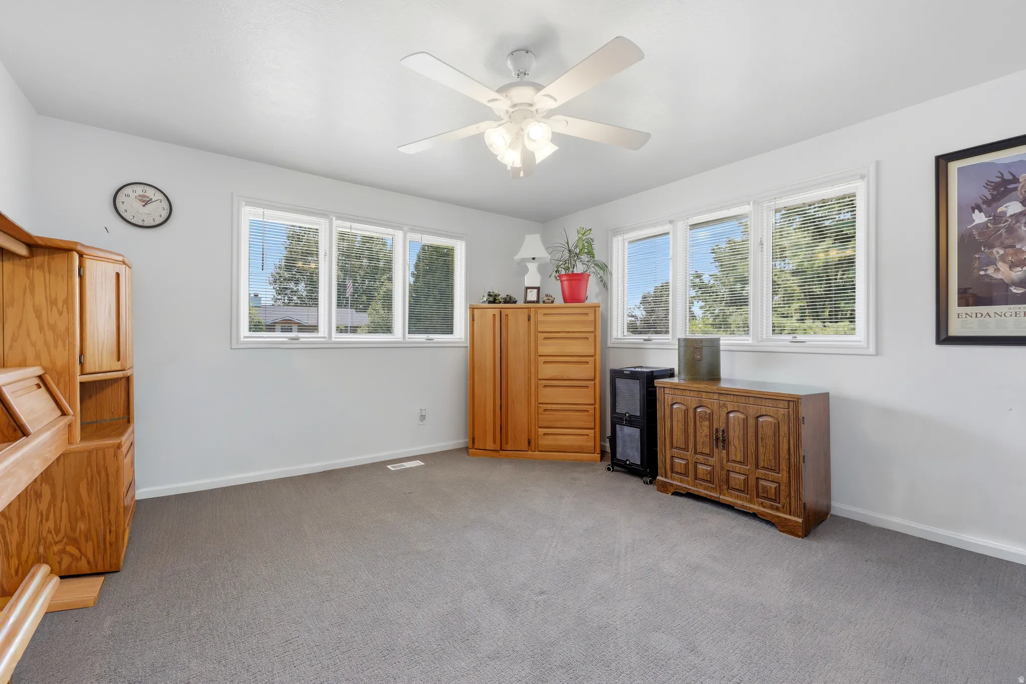 Room featuring light gray carpeting, neutral wall paint, white trim, and a white ceiling fan with integrated lighting