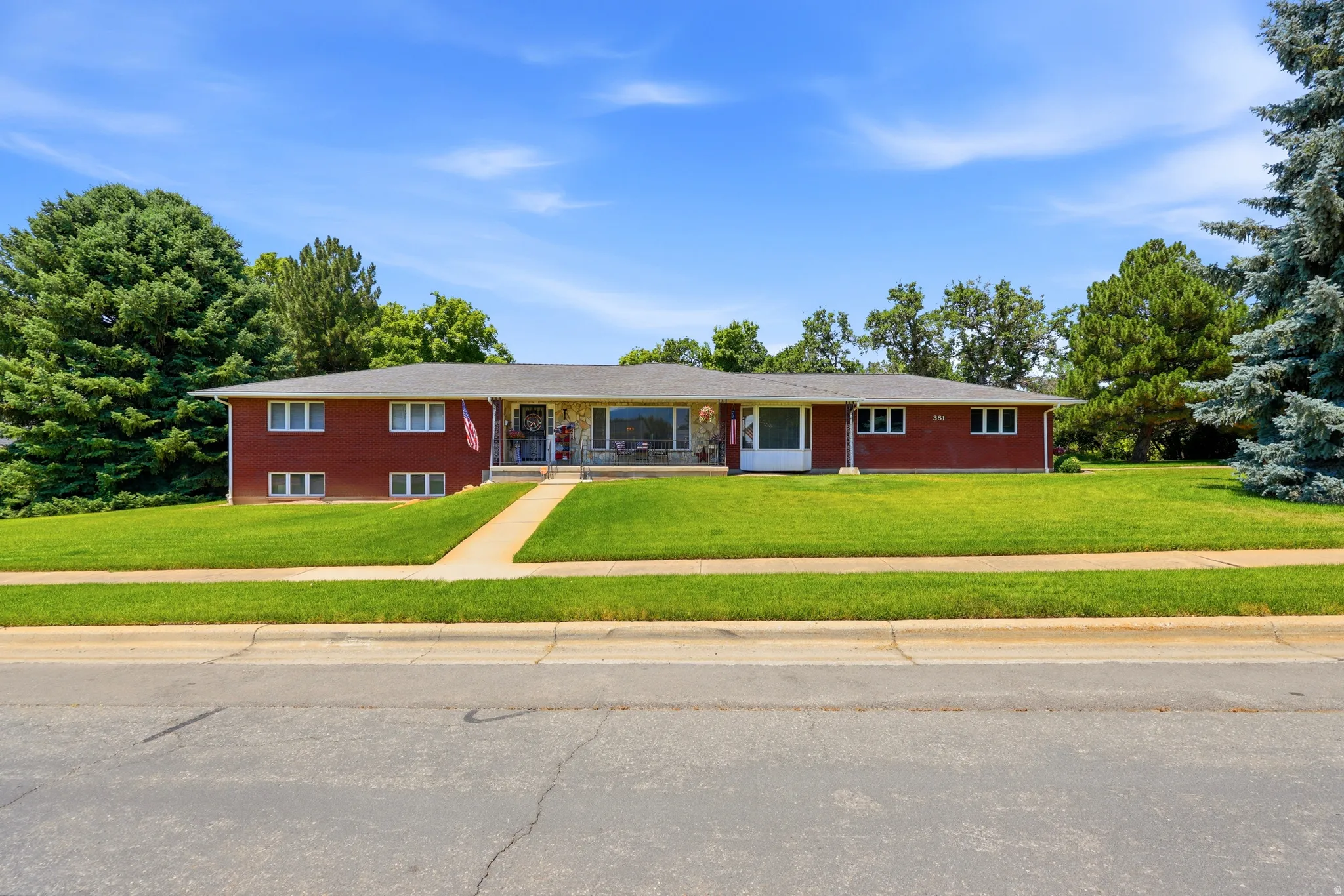 Split-level residence featuring a red brick exterior, a paved walkway, and a spacious front lawn