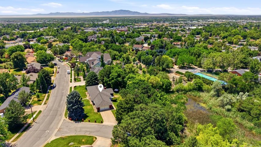 Property situated on a street with mature trees and green landscaping, featuring a paved driveway and a two-car garage