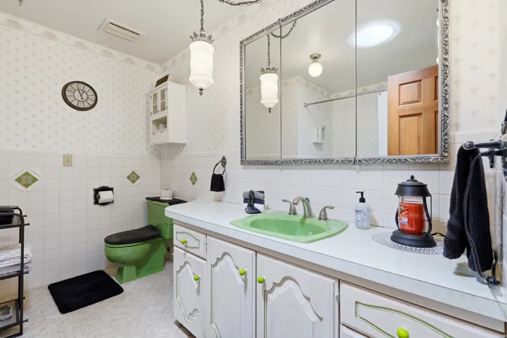 Bathroom vanity featuring a green basin, dual-handle faucet, and white countertop