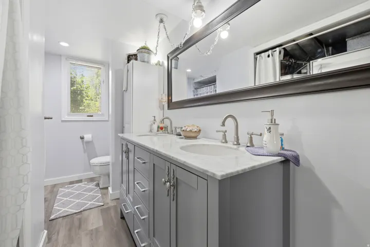 Double vanity featuring a light gray base cabinet, white countertop, and dual undermount sinks with brushed nickel faucets