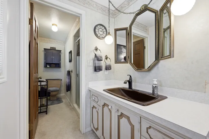 Bathroom featuring a vanity with a dark brown integrated sink, white countertop, and antique brass framed mirror