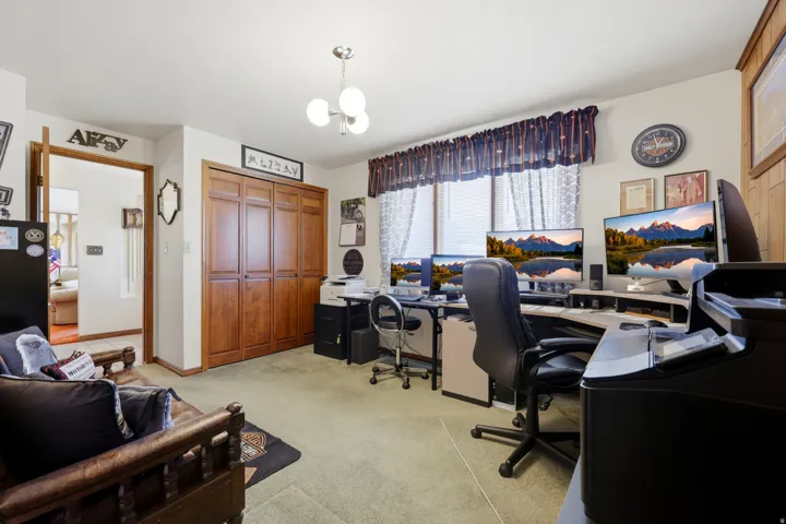 Spacious interior room featuring light green carpeting and a wall of wood-finish bi-fold closet doors