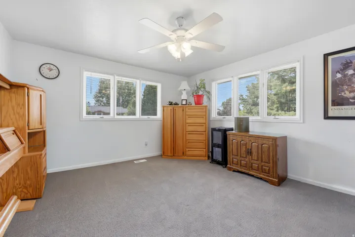 Room featuring light gray carpeting, neutral wall paint, white trim, and a white ceiling fan with integrated lighting
