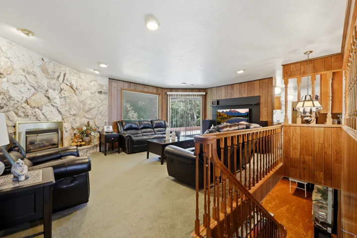 Living area featuring a stone accent wall with an inset fireplace, wood-paneled walls, and soft carpeting