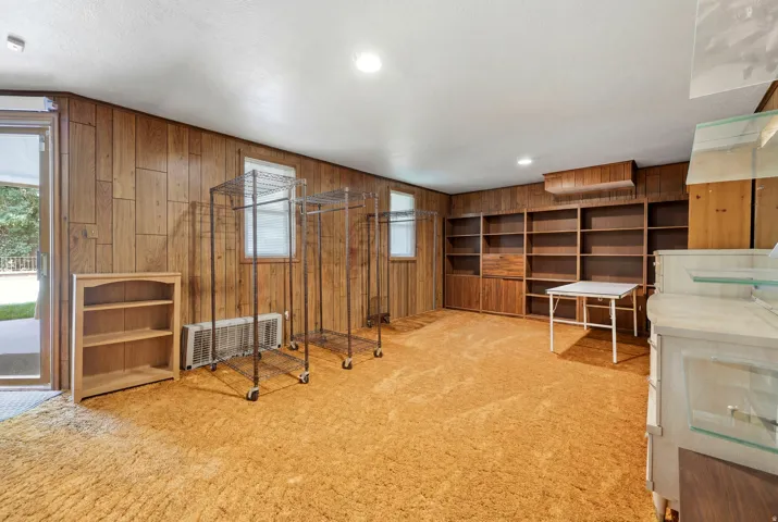 Spacious room featuring wood paneling, built-in shelving, plush carpeting, and recessed lighting