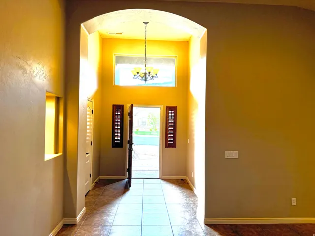 Grand entryway featuring an arched ceiling, a decorative chandelier, and a transom window