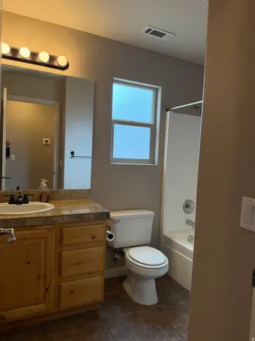 Bathroom featuring a single vanity with wood cabinetry, a light-toned countertop, and a white basin sink