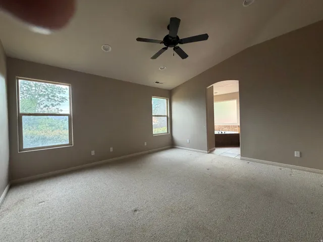 Spacious room featuring vaulted ceilings, recessed lighting, and a ceiling fan
