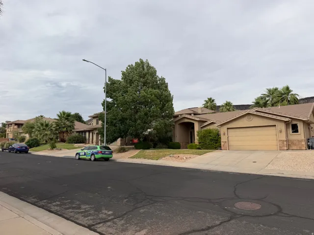 Stucco exterior home featuring a two-car garage, arched entry, and mature landscaping
