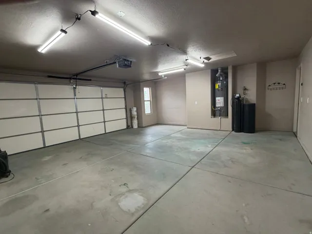 Spacious garage featuring a sectional overhead door, exposed concrete flooring, and multiple overhead fluorescent light fixtures