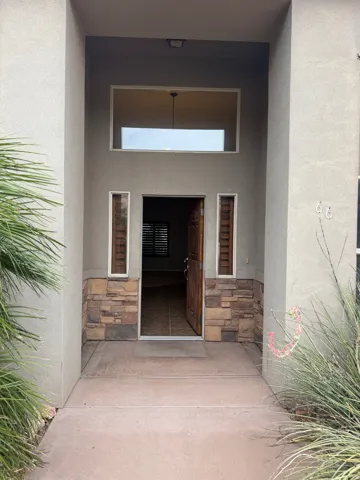 Inviting entry featuring a solid wood door, stone facade accents, and transom window