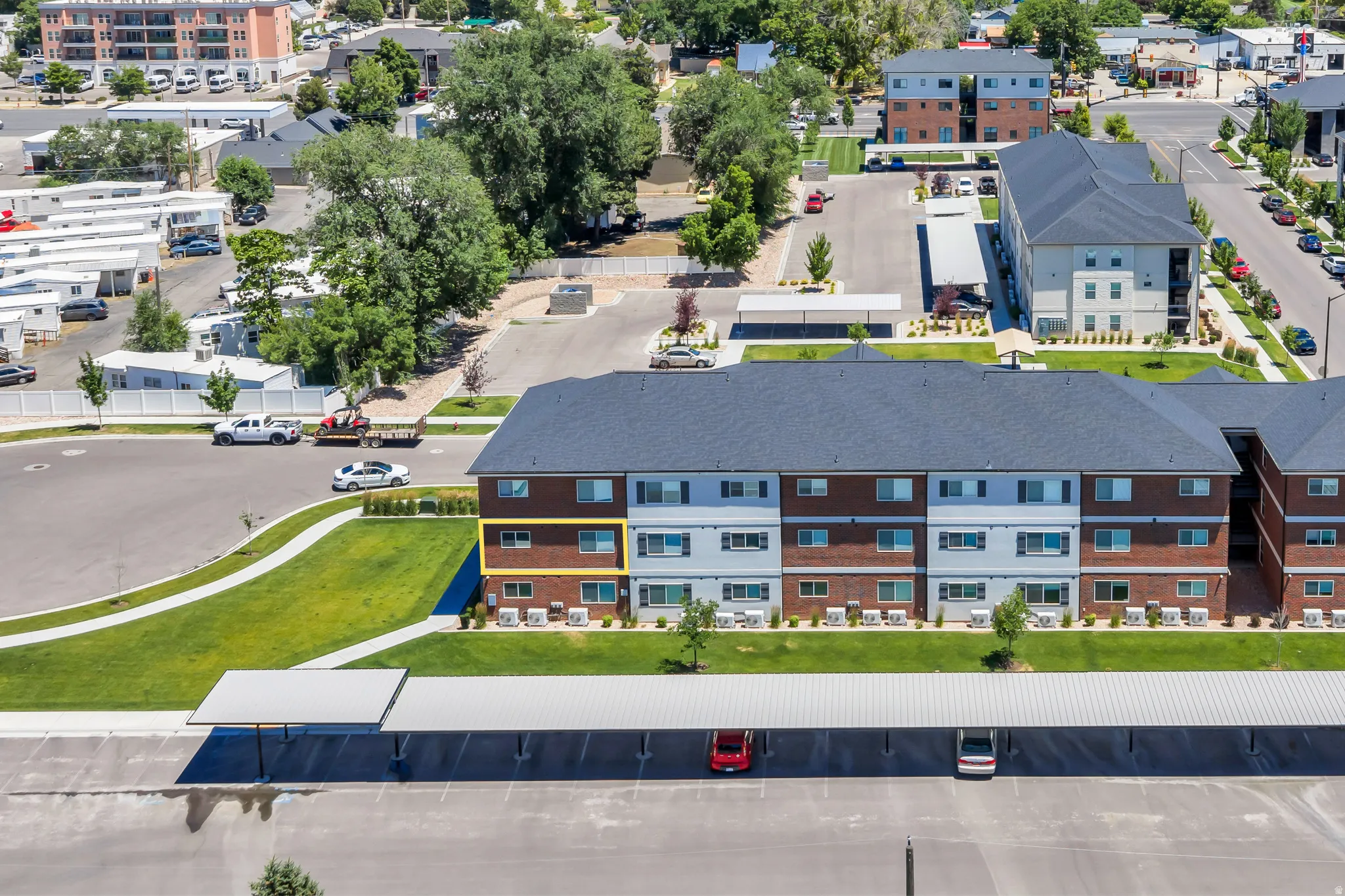 Multi-story building featuring a dark gray shingle roof and a brick facade with light gray siding accents