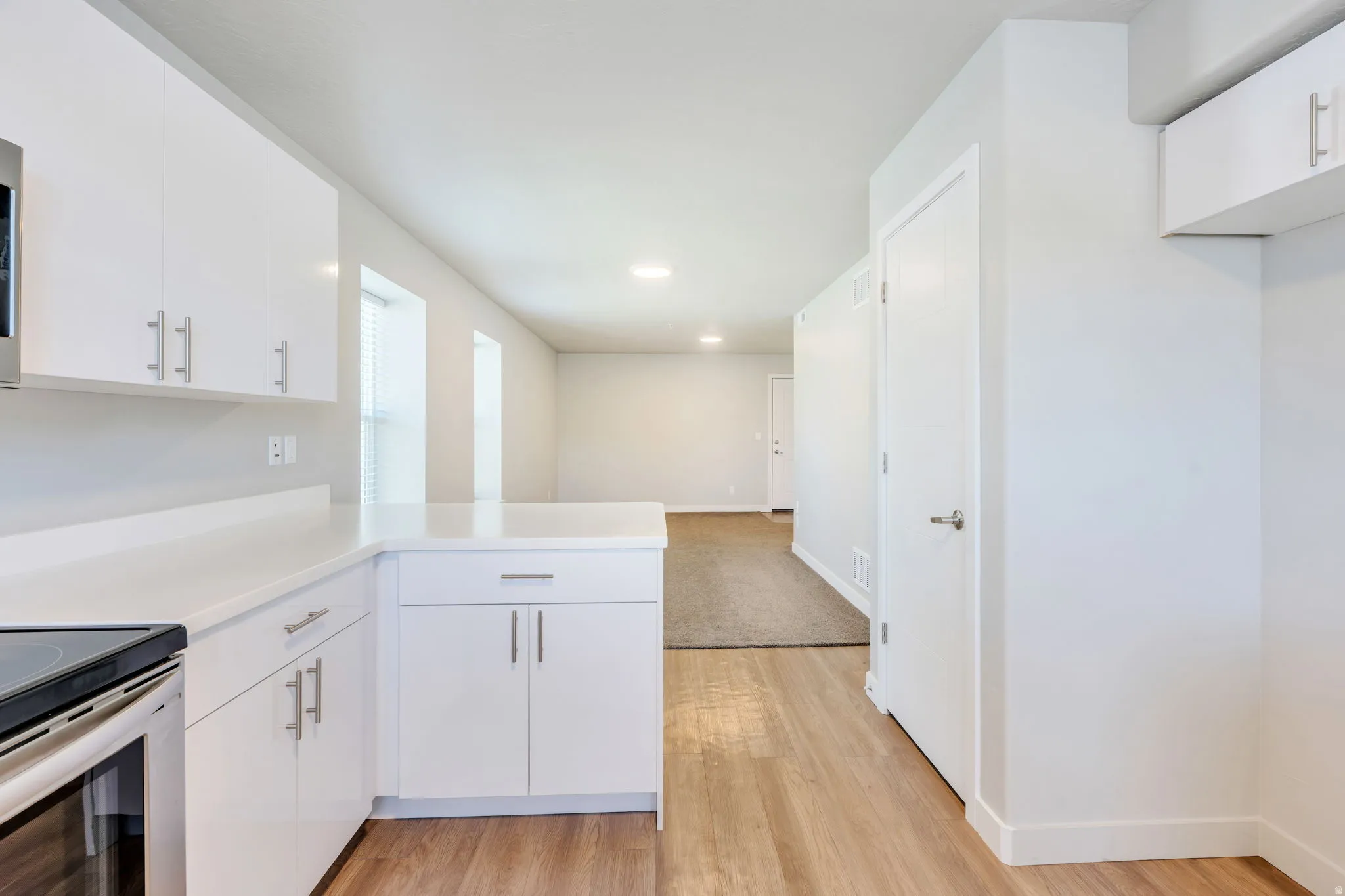 Kitchen featuring white cabinetry, light-toned countertops, and wood-finish flooring