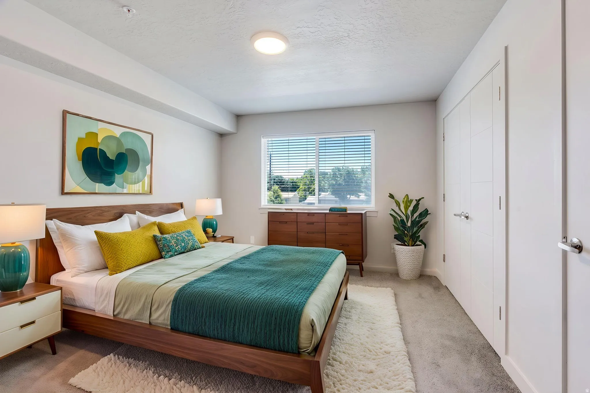 Bedroom featuring a large window with blinds, light gray carpet, and white walls