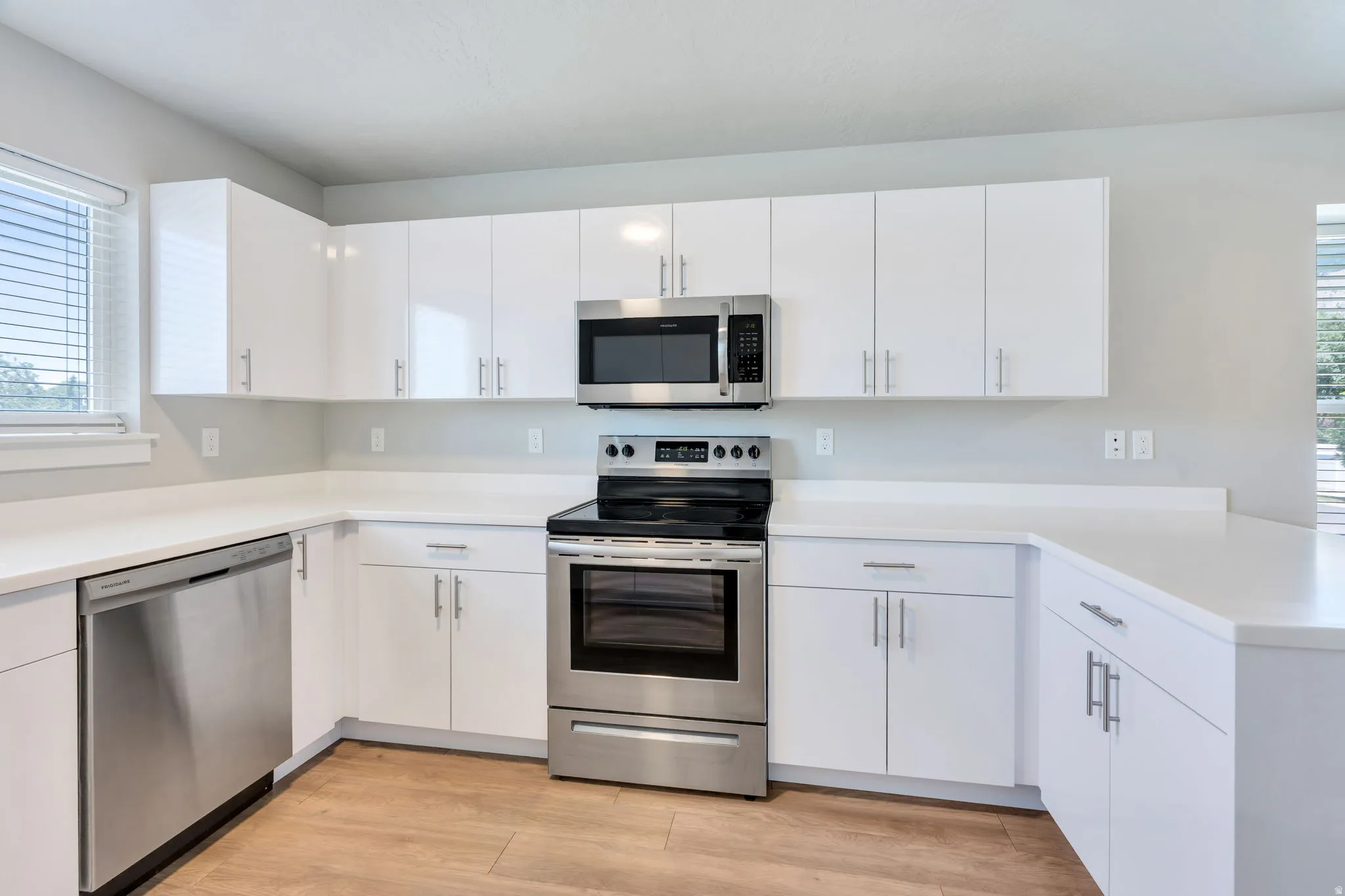 Modern kitchen featuring white shaker-style cabinetry and light-toned countertops