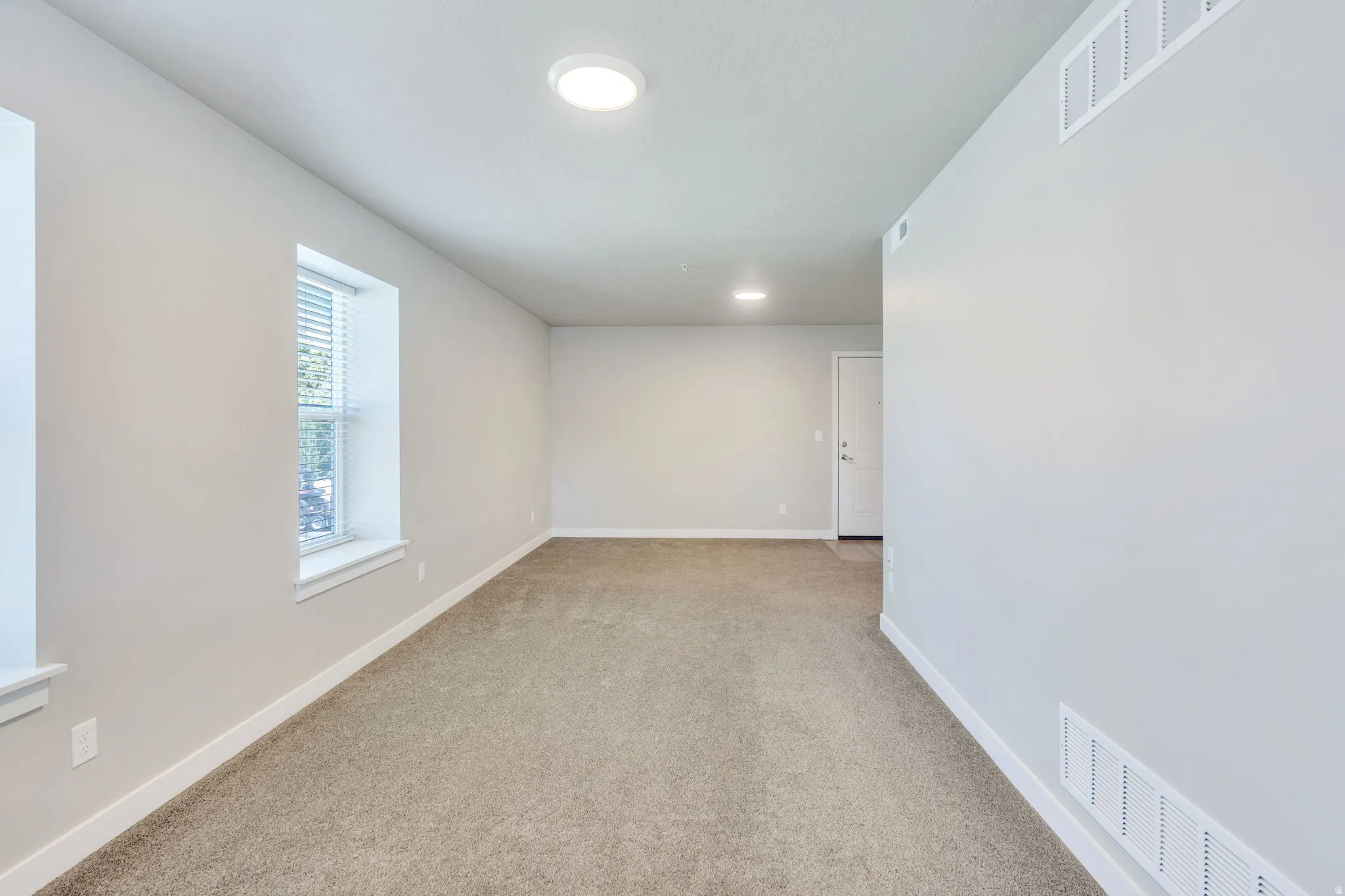 Carpeted room featuring a white door, recessed lighting, and a window with blinds
