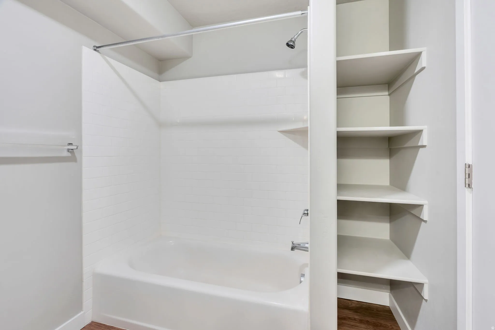 White subway tile shower surround with a built-in corner shelf and polished chrome fixtures